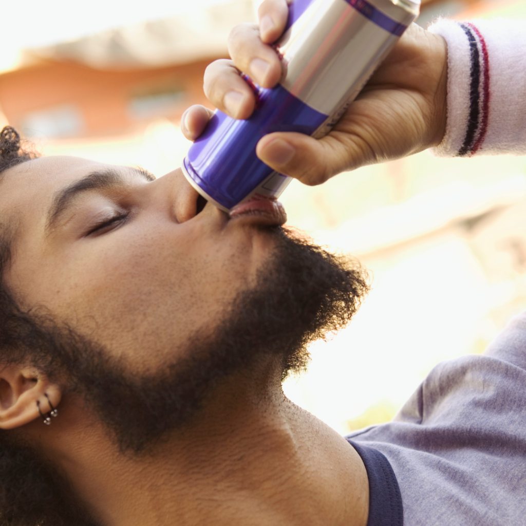 close up of a man drinking an energy drink from a can