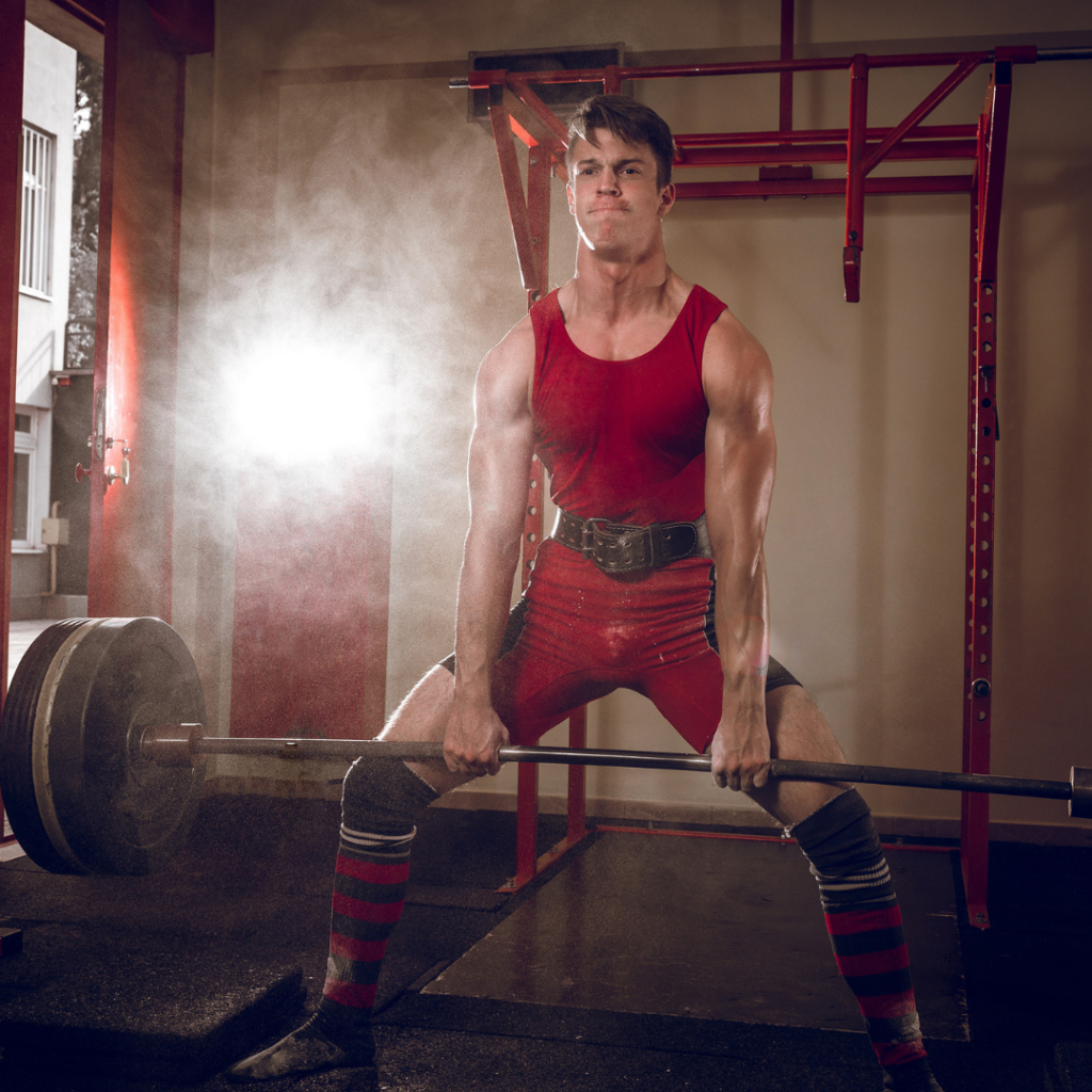 man in red gym outfit performing sumo deadlifts