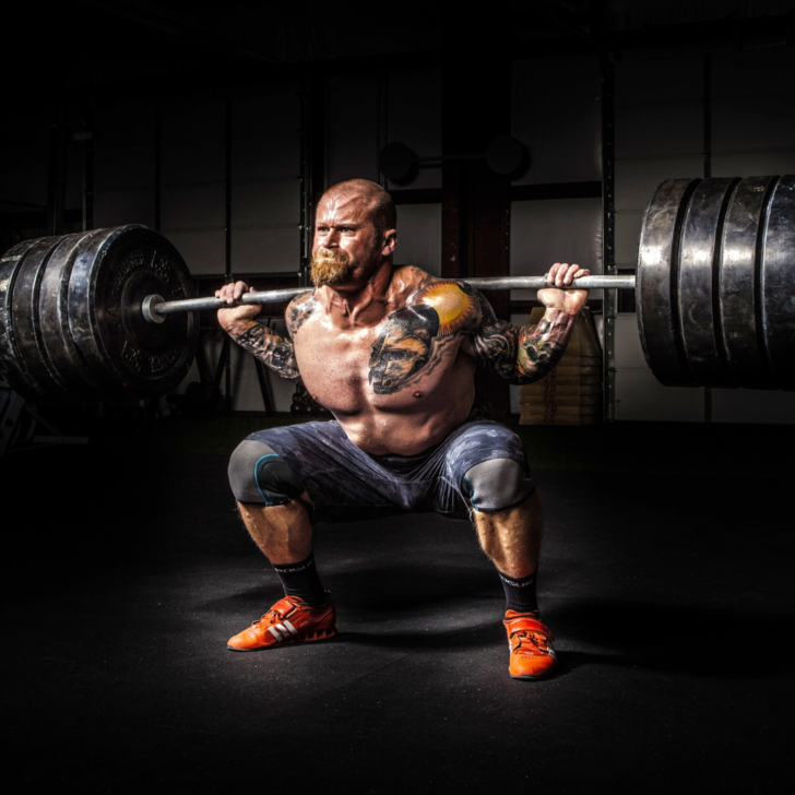 muscular man doing heavy barbell squats