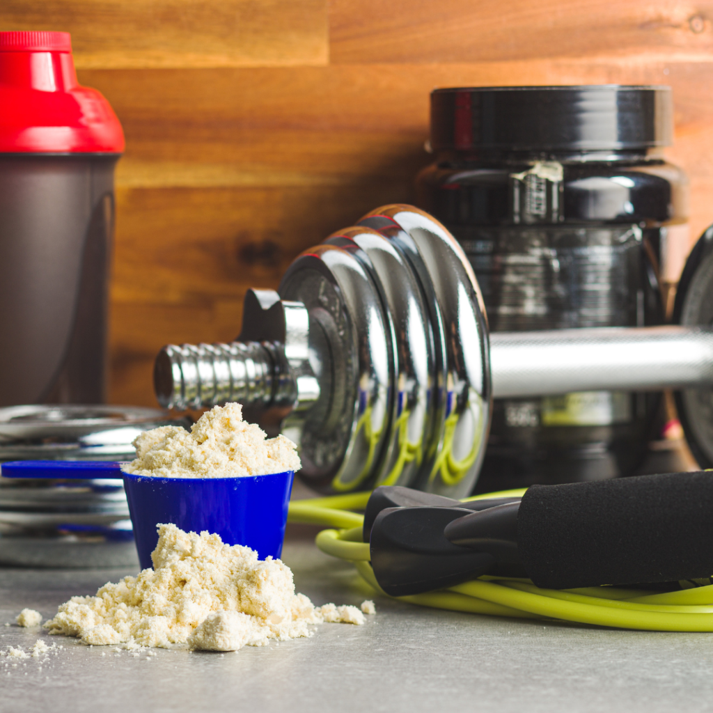 image of a protein powder scoop with weights in the background