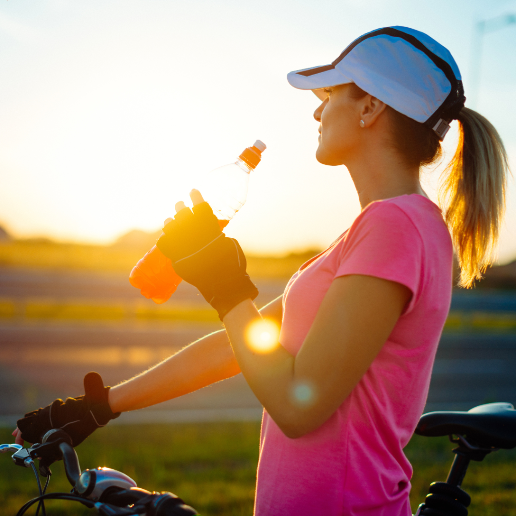 woman on a bicycle drinking an energy drink from a bottle